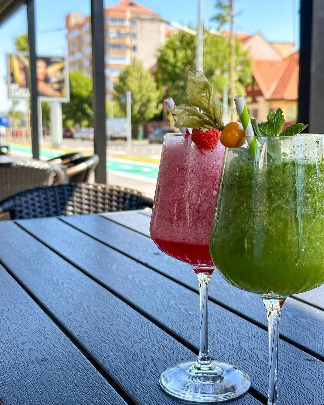 Două limonade pe o masă de pe terasă, cu strada în spate.