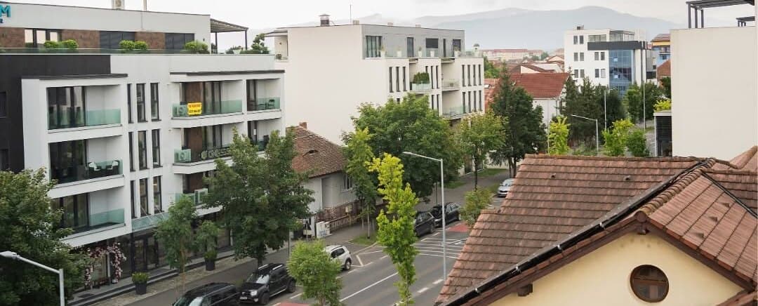 Acoperișuri și clădiri din jur, cu munții în depărtare.